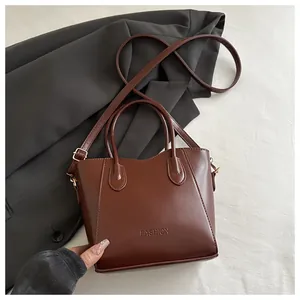 Macro view of brown leather bucket bag showing the embossed fashion text and gold hardware