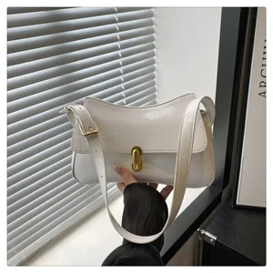 Close-up of a white patent leather shoulder bag with a gold twist lock and wavy edge