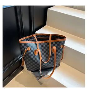 Dettaglio della borsa tote a scacchi con cinturini in pelle marrone e fibbia in metallo