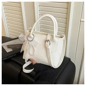 Detail of off-white lychee leather bucket bag with pearl lace charm and shoulder strap