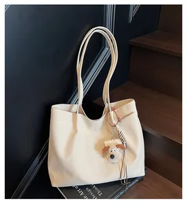 Détail du cabas en toile blanc cassé avec broderie et breloque en peluche chien