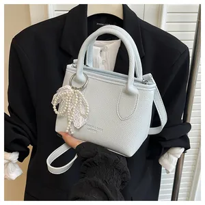 Close-up of light blue bucket bag featuring lace bow and pearl charm details