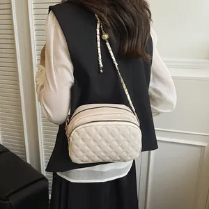 Borsa a tracolla trapuntata beige con catena dorata e sfera decorativa sulla modella