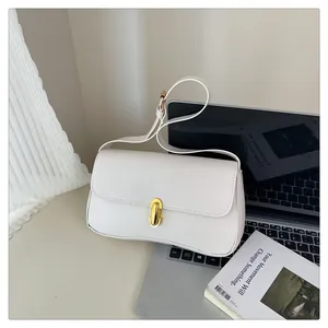 Detailed view of white leather shoulder bag with elegant oval gold buckle on a laptop