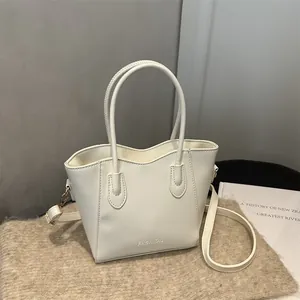 Elegant white bucket bag with double handles and FASHION lettering in a studio setting
