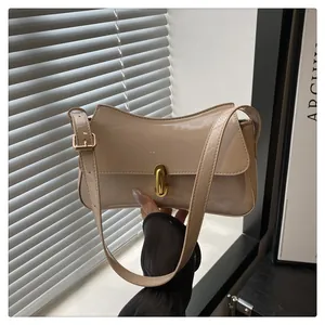 Detail of glossy beige patent leather saddle bag with gold metal twist-lock and wavy edge
