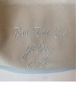 Gros plan sur la toile de coton beige avec des broderies de lettres blanches