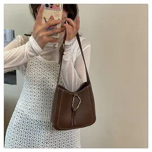 Detail of dark brown PU leather bag with white contrast stitching and gold buckle