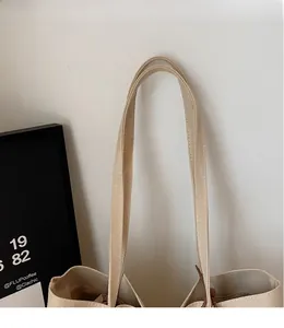 Détail de la bandoulière en toile blanc cassé lisse sur un sac cabas minimaliste