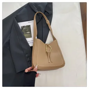 Detail of camel leather shoulder bag with gold wave buckle, tassels and contrast stitching