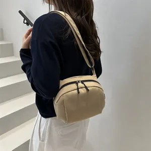 Minimalist khaki nylon shoulder bag with dual zipper closure and adjustable strap