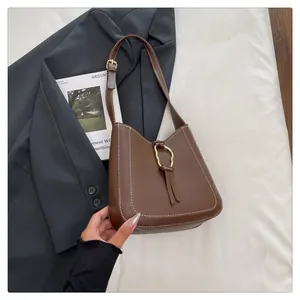 Detailed shot of brown leather bag with white contrast stitching and gold metal buckle