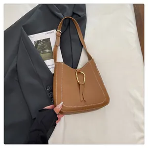 Detail of brown leather handbag with contrast stitching and golden ring tassel decoration