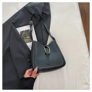 Detail of black bucket bag with contrast stitching and golden wavy metal buckle accent