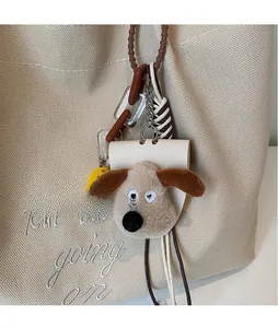 Gros plan d'un joli pendentif chien en peluche avec broderie sur un sac fourre-tout beige