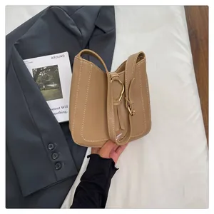 Detail of khaki bucket bag with contrast stitching, heart buckle, and leather fringe