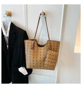 Détail d'un cabas en cuir marron à motif ours avec pochette suspendu au mur