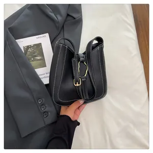 Detail of black bucket bag featuring white contrast stitching and a decorative tassel