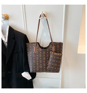 Détail du cabas imprimé avec pochette montrant le monogramme d'ours et les lanières