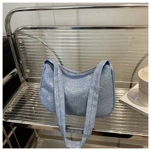 Detail of light blue denim shoulder bag with colorful bow prints on acrylic shelf