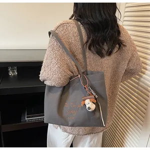 Détail du sac cabas en toile grise avec broderie marron et porte-clé chiot en peluche