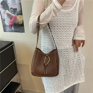 Brown leather bucket bag with white contrast stitching and gold buckle detail on crossbody