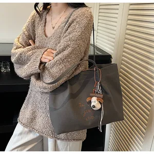 Détail de la broderie et du pendentif chien en peluche sur le sac cabas gris foncé