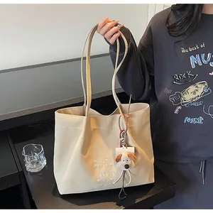 Détail du sac cabas en toile crème avec broderie blanche et charmant pendentif de chien en peluche