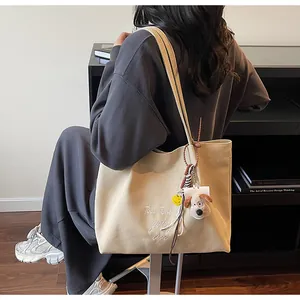 Détail du sac cabas en toile beige avec broderie de lettres et jolis accessoires en peluche