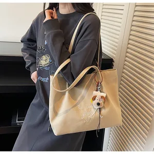 Détail des lettres brodées sur un sac fourre-tout en toile beige avec charme peluche