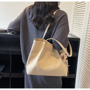 Détail du sac cabas en toile crème avec broderie de lettres et breloque chien