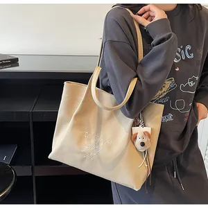 Détail du cabas en toile avec lettres brodées et un charmant petit chien en peluche
