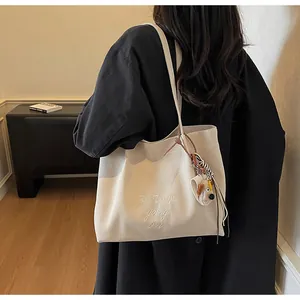 Détail du sac cabas en toile avec broderie blanche et breloque en peluche pour chien