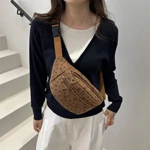 Brown corduroy crossbody bag with bow patterns shown on a model in a minimalist setting