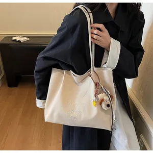 Détail du sac cabas en toile crème avec broderie et adorable pendentif chiot en peluche