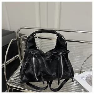 Detail der schwarzen Schleifenhandtasche mit silbernen Reißverschlüssen auf Gitterstuhl