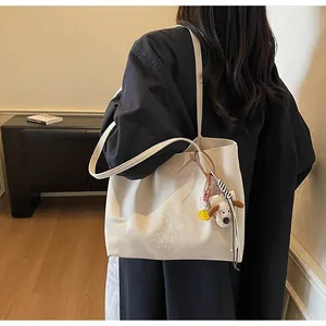 Détail du sac cabas en toile avec broderie et breloque chiot en peluche