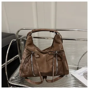 Detailansicht der braunen Hobo-Tasche mit Schleifen und silbernen Reißverschlüssen