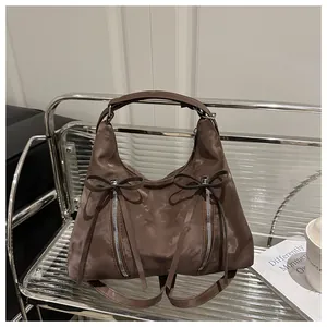 Detailansicht der braunen Hobo-Tasche mit Satin-Finish, Doppel-Zippern und Schleifen