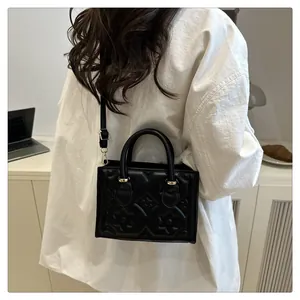 Close-up of black crossbody bag with embossed floral texture on model's side view