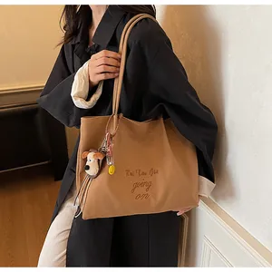 Détail du sac fourre-tout caramel avec broderie et charmant pendentif en forme de chiot
