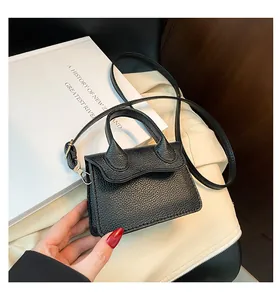 Détail du mini sac noir à bandoulière avec rabat ondulé et texture en cuir litchi grainé