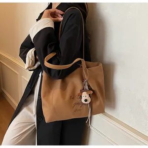 Détail du sac fourre-tout en toile marron avec broderie et pendentif chien en peluche