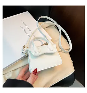 Gros plan d'un mini sac blanc avec motif litchi et rabat ondulé posé sur des livres