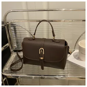 Close-up of dark brown lychee leather handbag with golden horseshoe metal buckle hardware