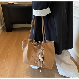Détail du sac cabas en toile kaki avec broderie cursive et charmant chiot en peluche