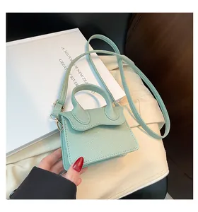 Détail du mini sac vert menthe en cuir grainé avec rabat ondulé et bijoux dorés