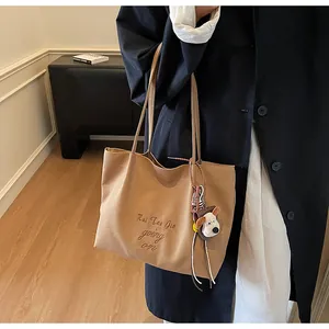 Détail d'un sac cabas en toile kaki avec broderie de lettres et pendentif chien