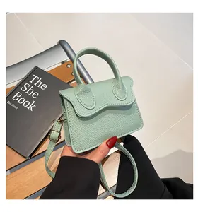 Détail du sac vert menthe en cuir grainé avec rabat ondulé et fermoir doré chic