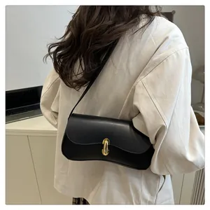 Chic black leather underarm bag with gold U-buckle worn by woman in beige blazer